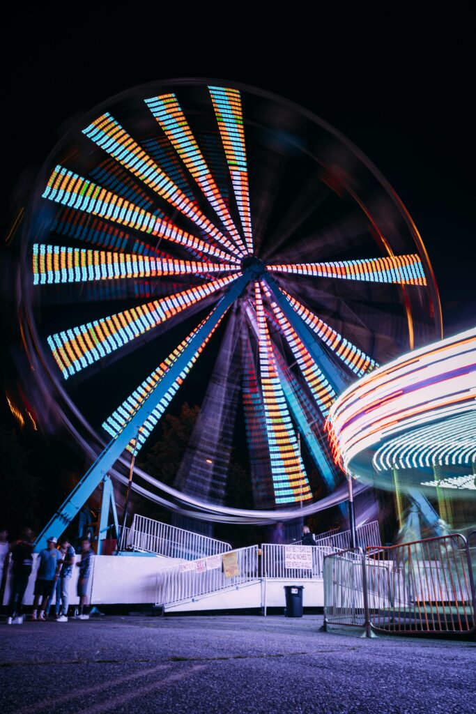 Vibrant Ferris wheel spinning at Kennewick fairground during a lively night festival.